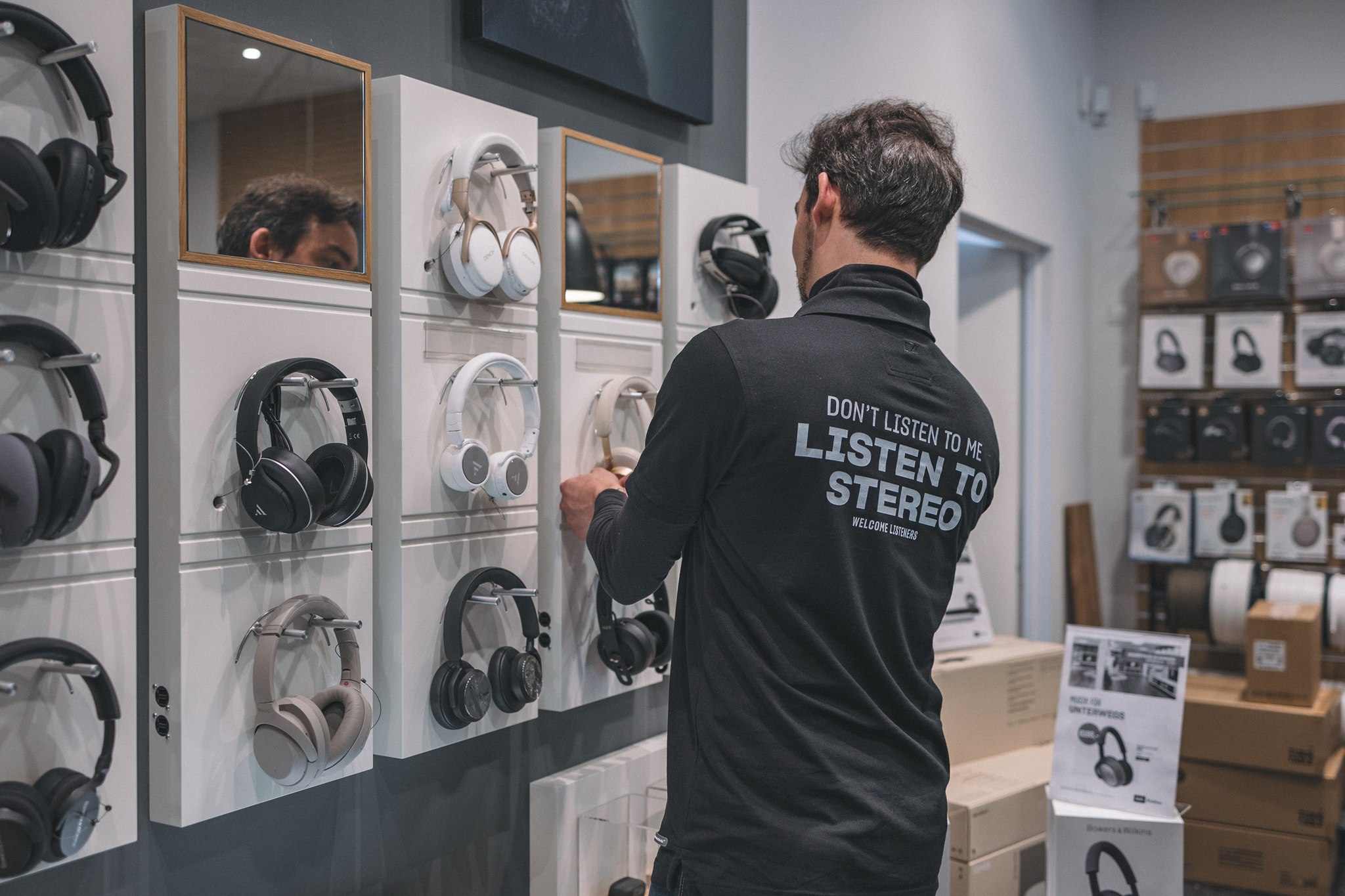 Medewerker bij een wand met koptelefoons