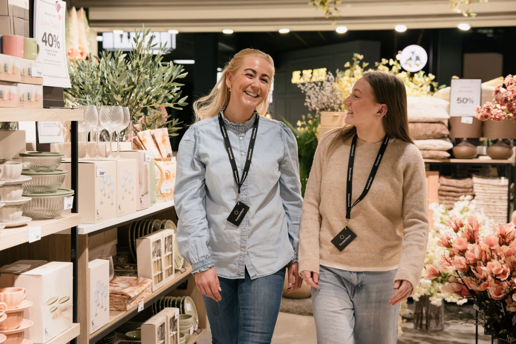 To selgere som går smilende sammen i butikk