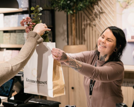 Selger som overrekker pose til kunde